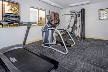 A treadmill and a weight machine in a room.